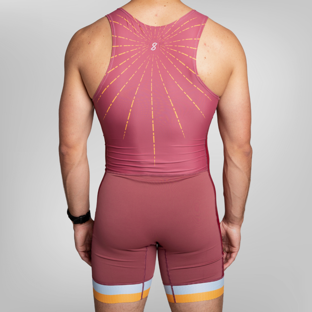 Rear view of a model wearing a maroon athletic unisuit with a yellow sunburst pattern on the back with yellow and white stripes at the hem of the trou.
