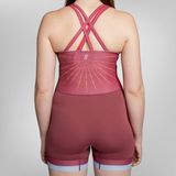 Rear view of a model wearing a maroon uni with crisscross back straps, a sunburst graphic.