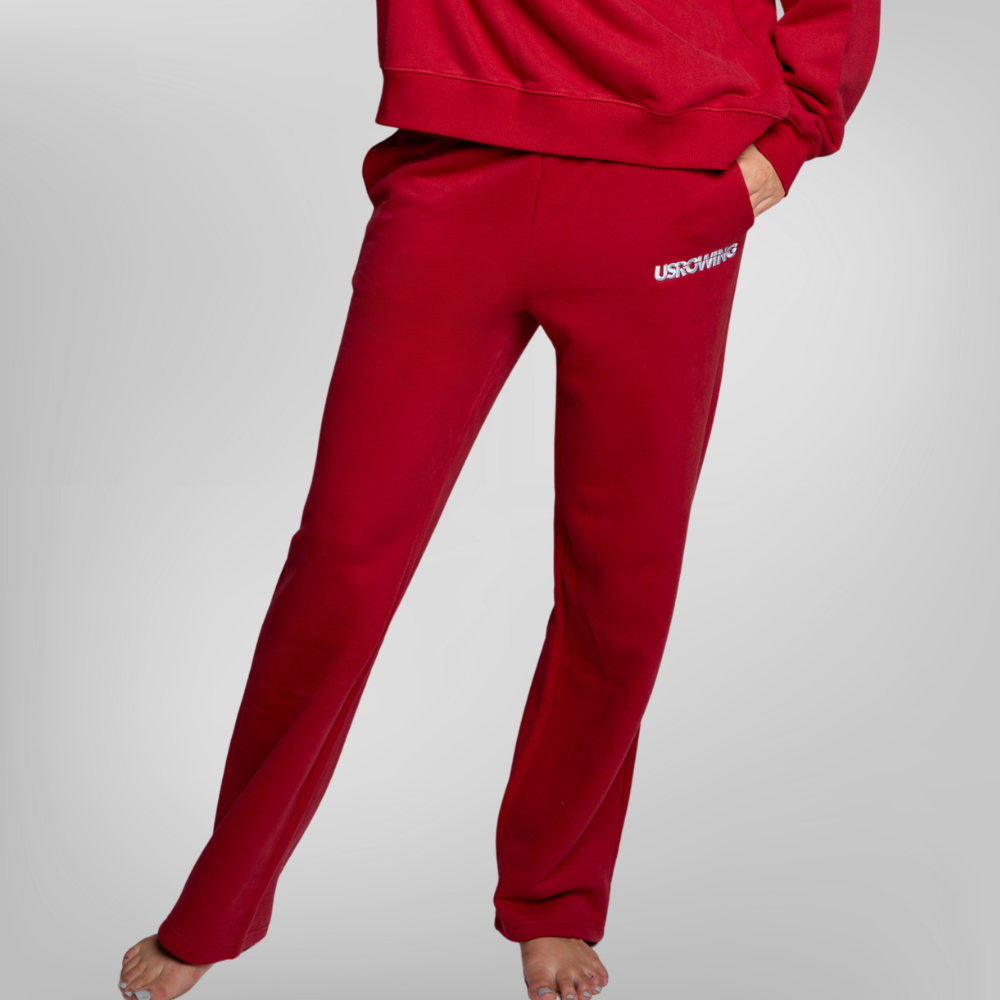 A person wearing red sweatpants and a matching red sweatshirt, shown from the waist down. The sweatpants have a small white USRowing logo on the left hip.