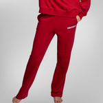 A person wearing red sweatpants and a matching red sweatshirt, shown from the waist down. The sweatpants have a small white USRowing logo on the left hip.