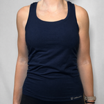 A woman wearing a dark navy blue knitted tank top with a scoop neck, shown from the shoulders to the waist against a light gray background.
