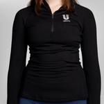 A woman wearing a black long-sleeve quarter-zip athletic top with a white USRowing branding logo on the left chest.