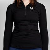 A woman wearing a black long-sleeve quarter-zip athletic top with a white USRowing branding logo on the left chest.