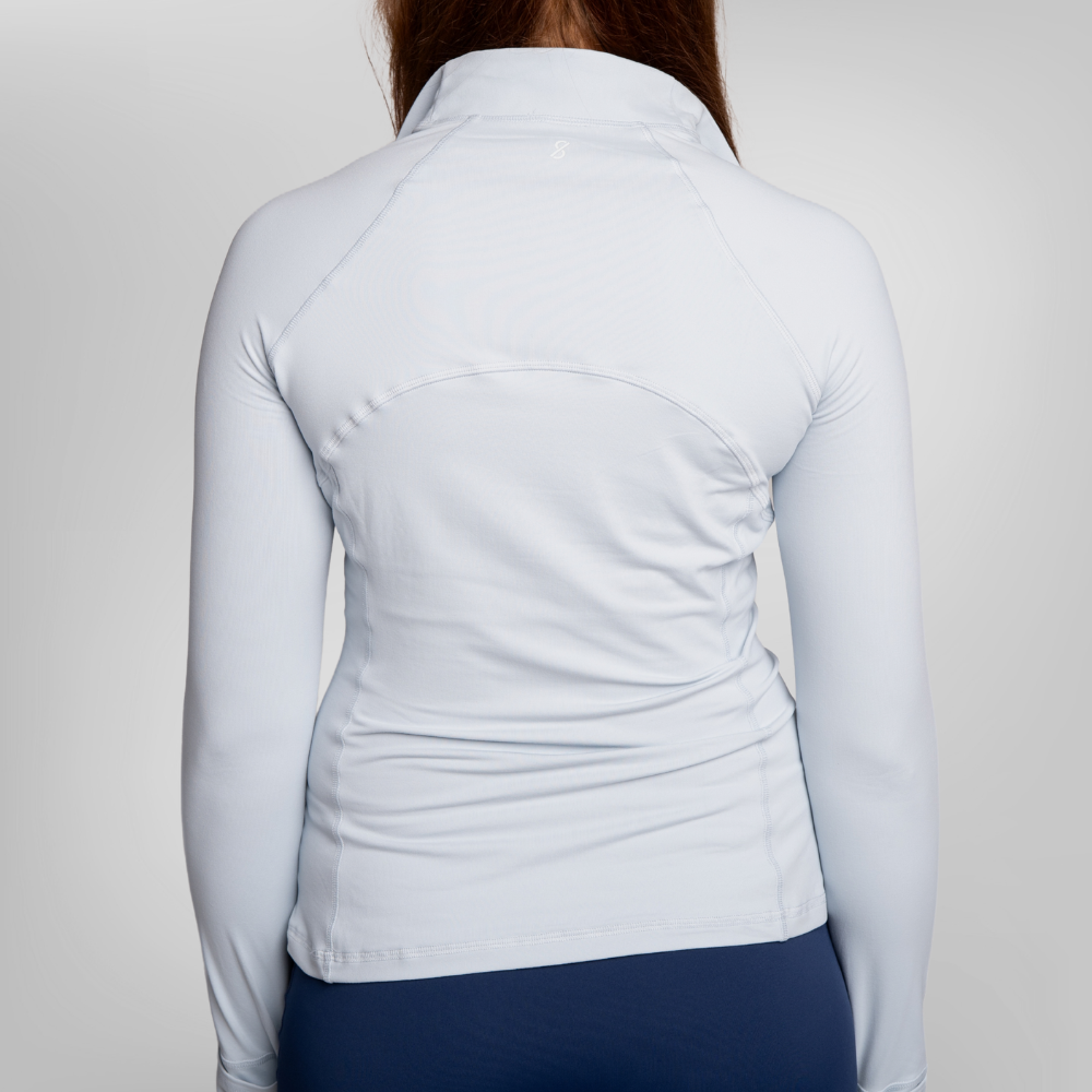 Back view of a woman wearing a light blue long-sleeve athletic top and navy blue trou.