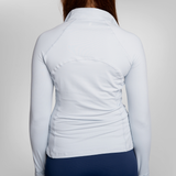 Back view of a woman wearing a light blue long-sleeve athletic top and navy blue trou.